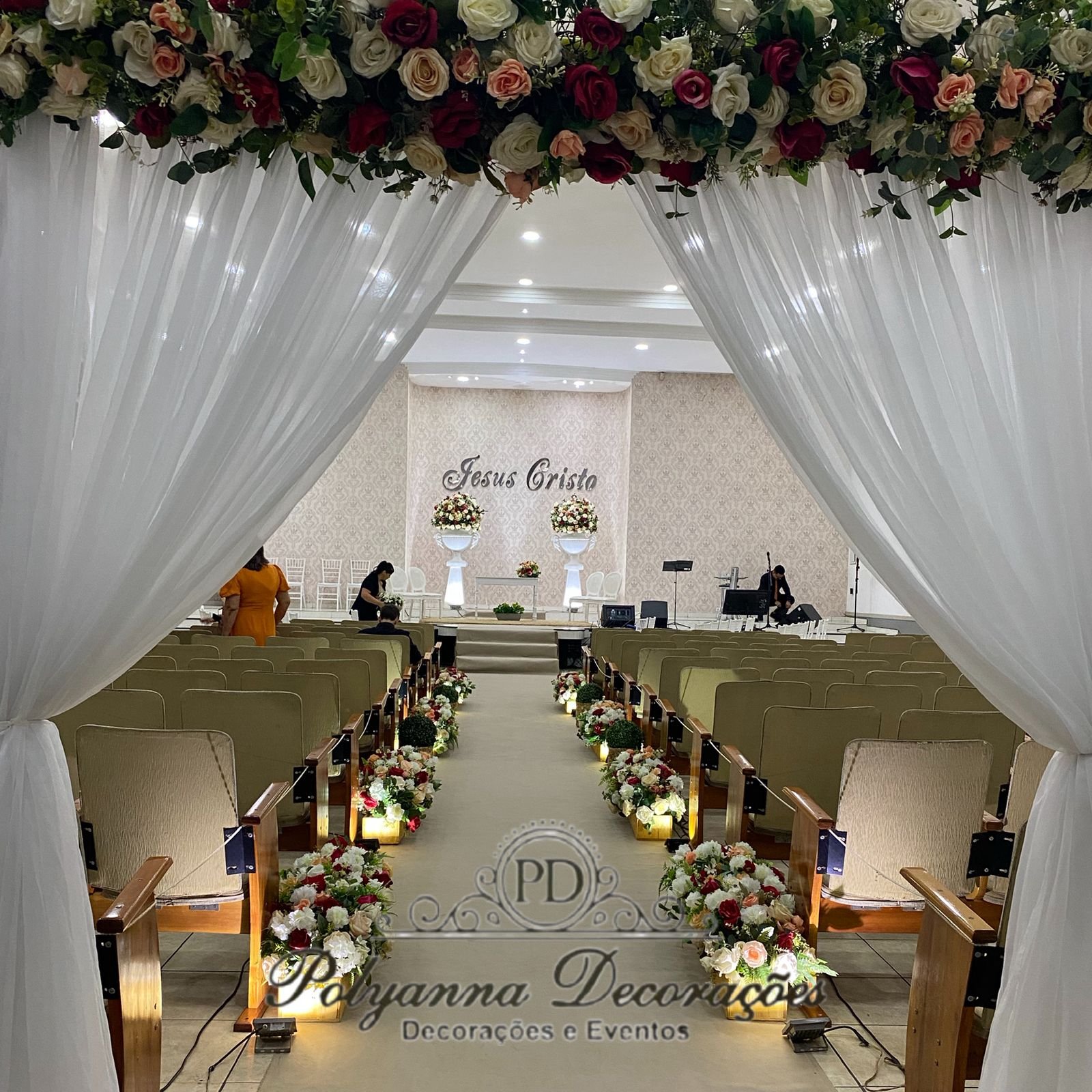 Passarela nave igreja com portal na entrada, altar com 2 arranjos Master no vasos áncoras e aparador, caminho com caixepós jardineira com flores artificiais e buxinhas